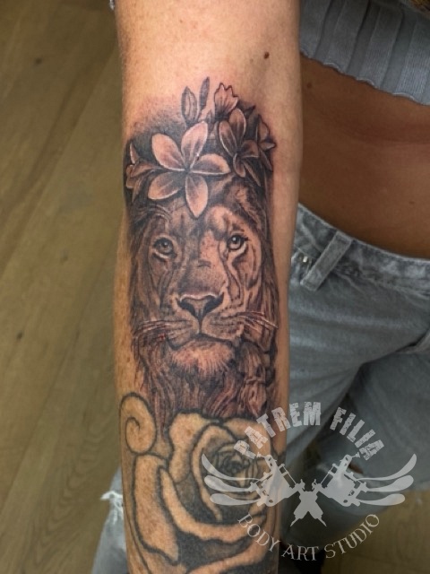 Leeuw met bloemen op onderarm Tattoeages