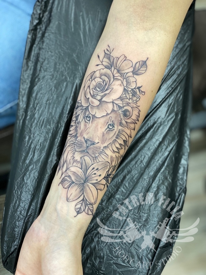 Leeuw met bloemen op onderarm Tattoeages