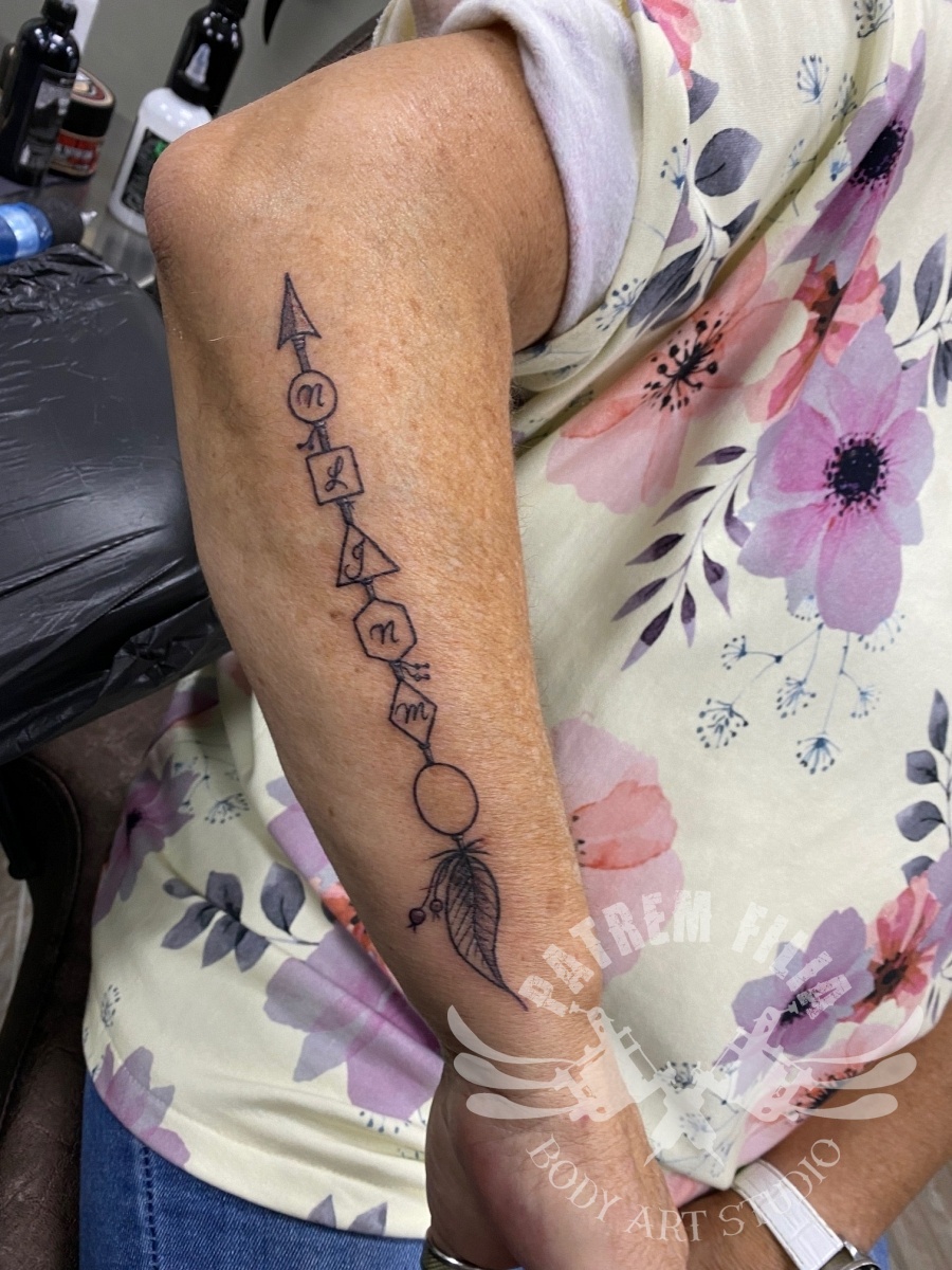 pijl met 1e letters kleinkinderen op onderarm Tattoeages