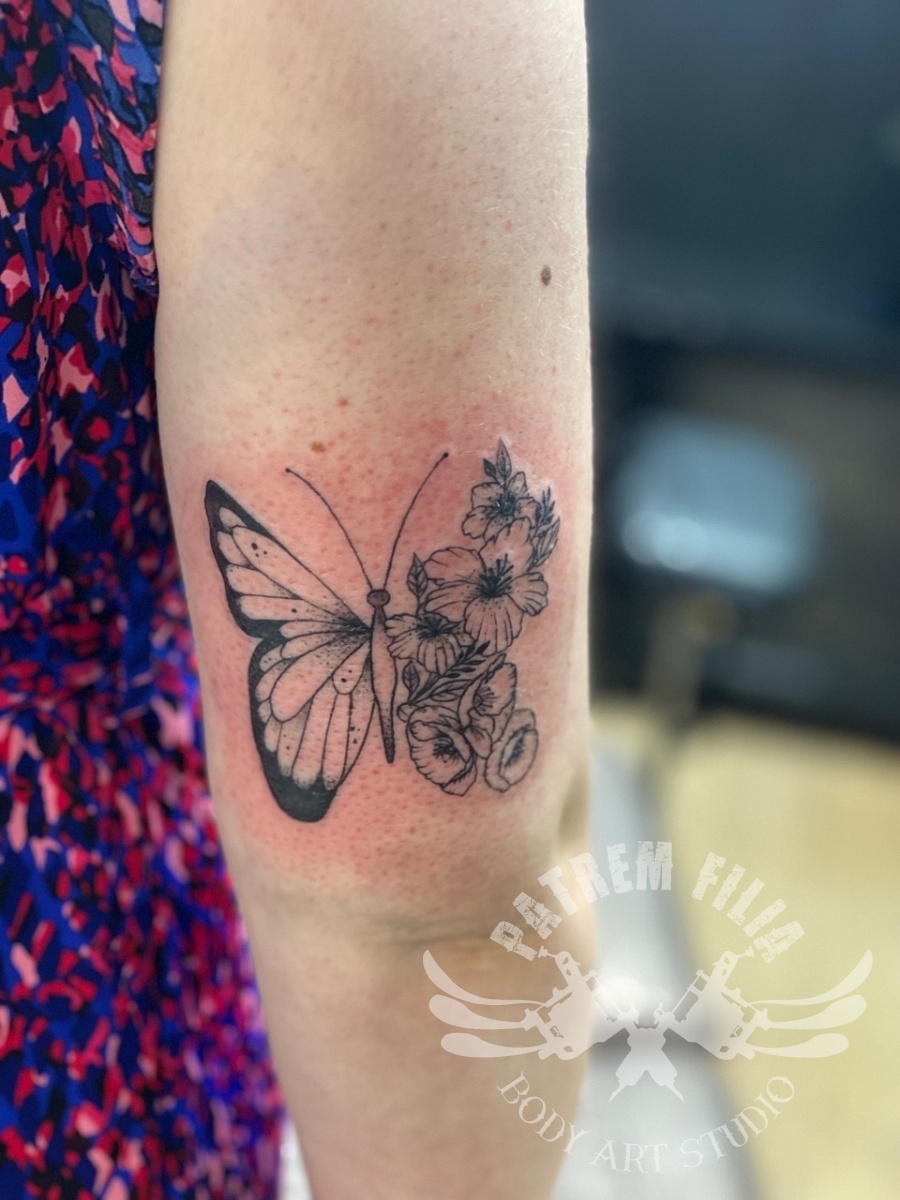 Vlinder met bloemen op bovenarm Tattoeages