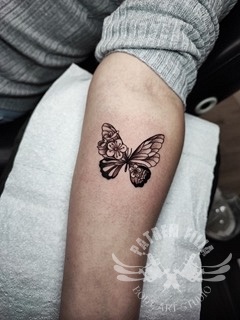 vlinder met wilde bloemen op onderarm Tattoeages