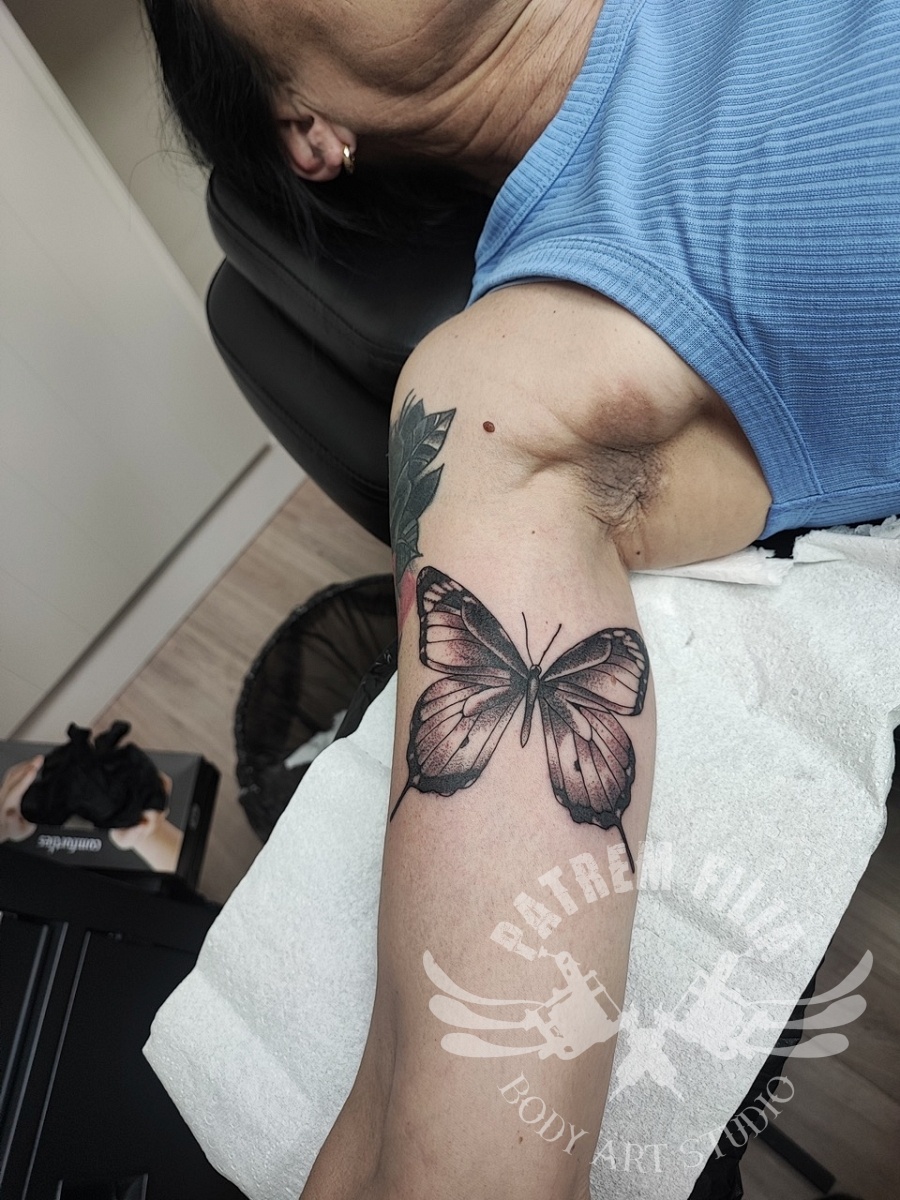 vlinder op biceps Tattoeages