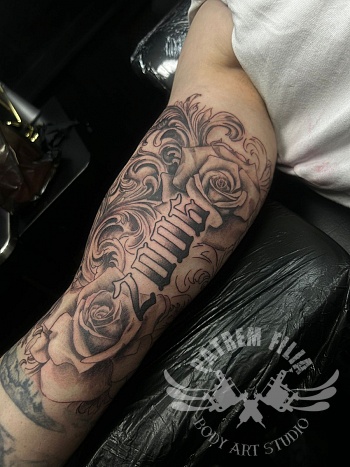 Black & grey rozen tattoo met lettering op de onderarm