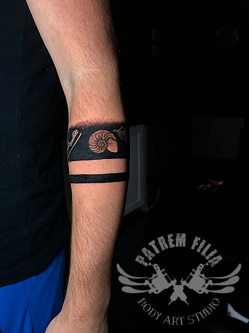Blackwork armband tattoo met nautilus schelp en dotwork details