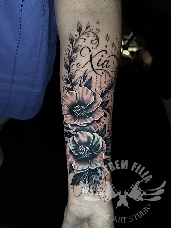 Bloemen sleeve tattoo met naam — elegant black & grey lijnwerk