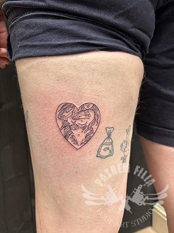 Fijne dijbeen tattoo met hartvorm en illustratief lijnwerk