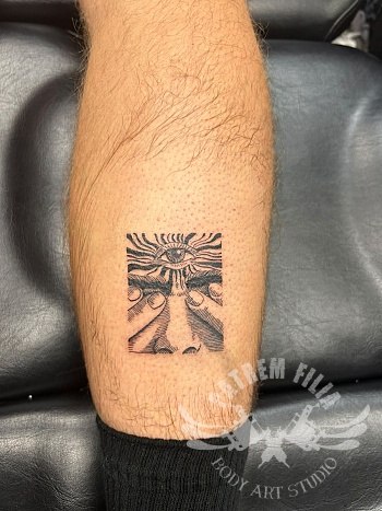 Graphic eye tattoo in etsstijl op kuit