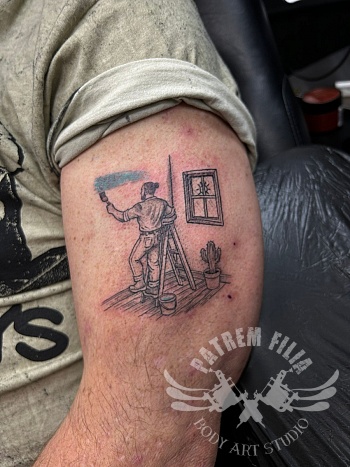 Illustratieve bovenarmtattoo met schilderend figuur en kleuraccent