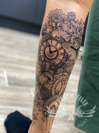 Klok met bloemen en mandala op onderarm.