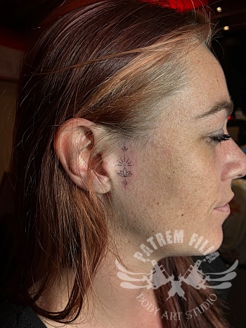 Minimalistische lotus tattoo naast het oor