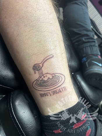 Minimalistische spaghetti tattoo met tekst op het onderbeen