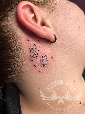 Minimalistische vlinder tattoo achter het oor