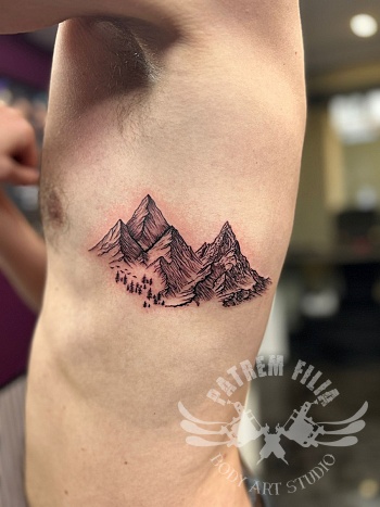 Ribcage tattoo met berglandschap in blackwork stijl
