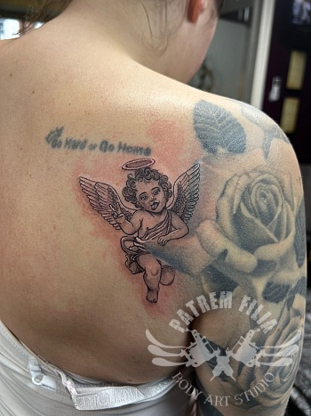 Speelse cherub tattoo met vleugels op de schouder