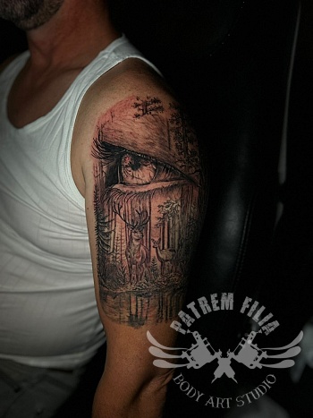 Surrealistisch oog in boslandschap bovenarm tattoo